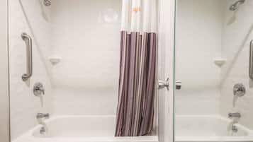 A modern bathroom with a glass shower enclosure, a white bathtub, and a striped shower curtain.
