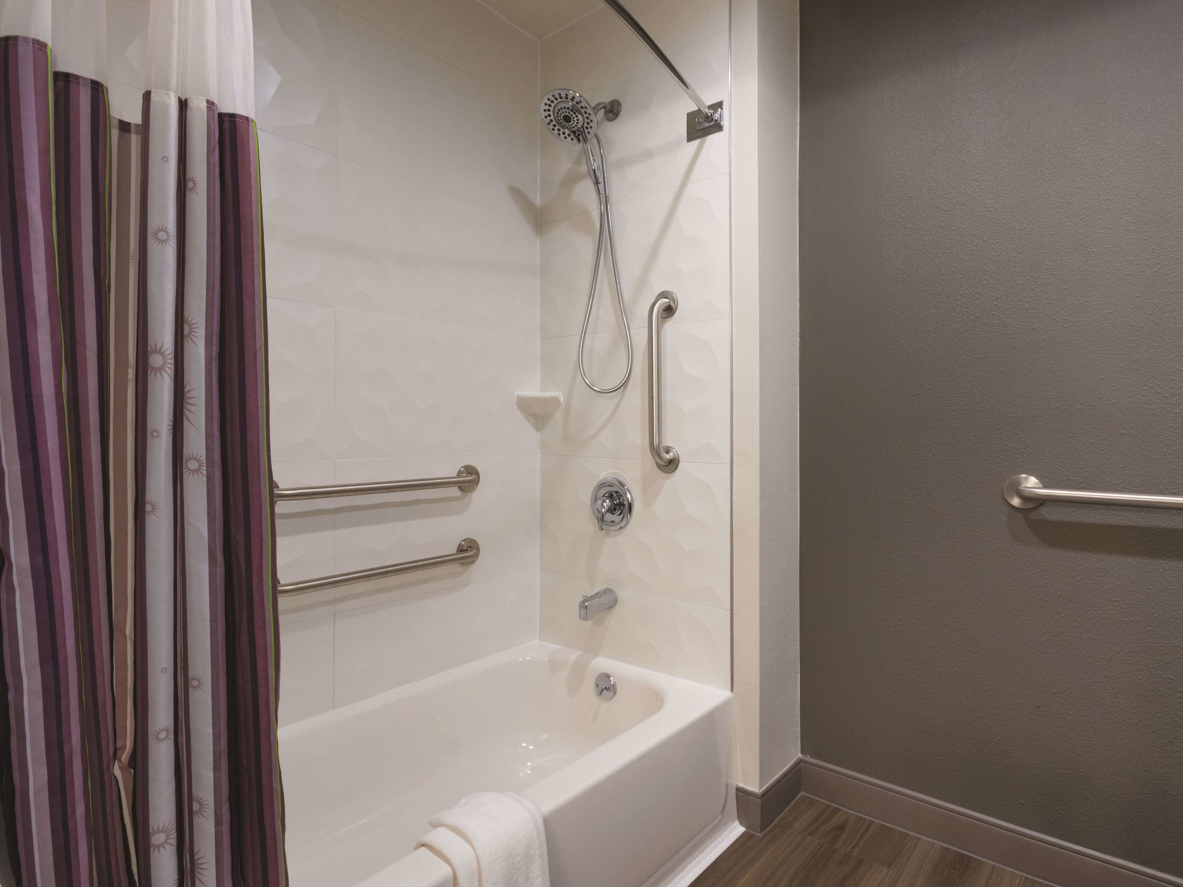 Une salle de bain équipée d’une baignoire, d’une douche et de barres d’appui.