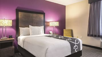 Habitación de hotel con una cama grande, dos mesitas de noche, una lámpara y una ventana con cortinas.