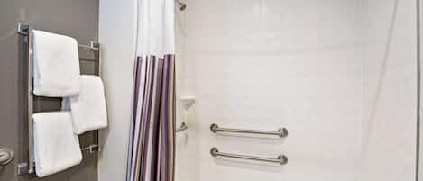 A shower with a white bathtub, a towel rack with white towels, and a striped shower curtain.