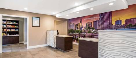 A hotel reception area with a cityscape mural, a snack bar, and a reception desk.