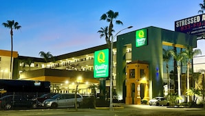 A hotel with a prominent 'Quality Inn & Suites by Choice Hotels' sign, a modern building with multiple floors, and a parking area with several cars.