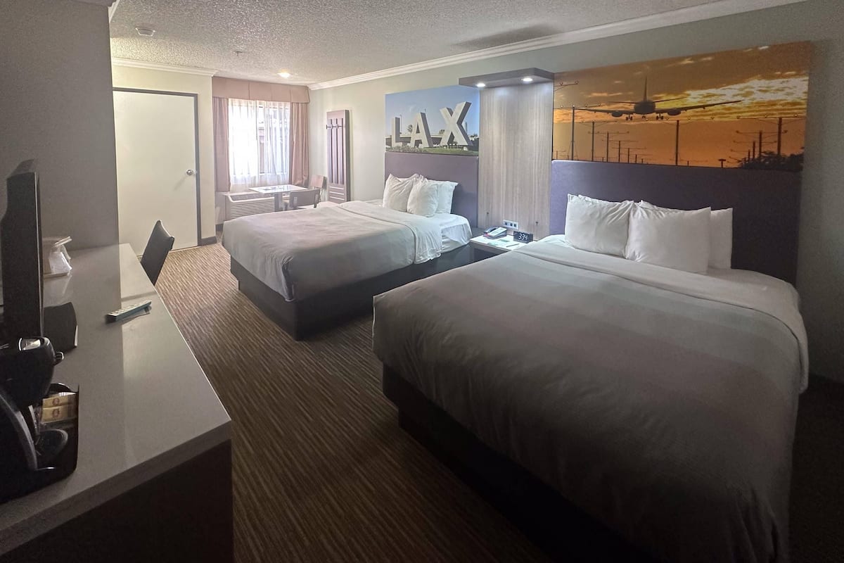 Ein Hotelzimmer mit zwei Betten, einem Schreibtisch mit Telefon und einem Bild an der Wand.