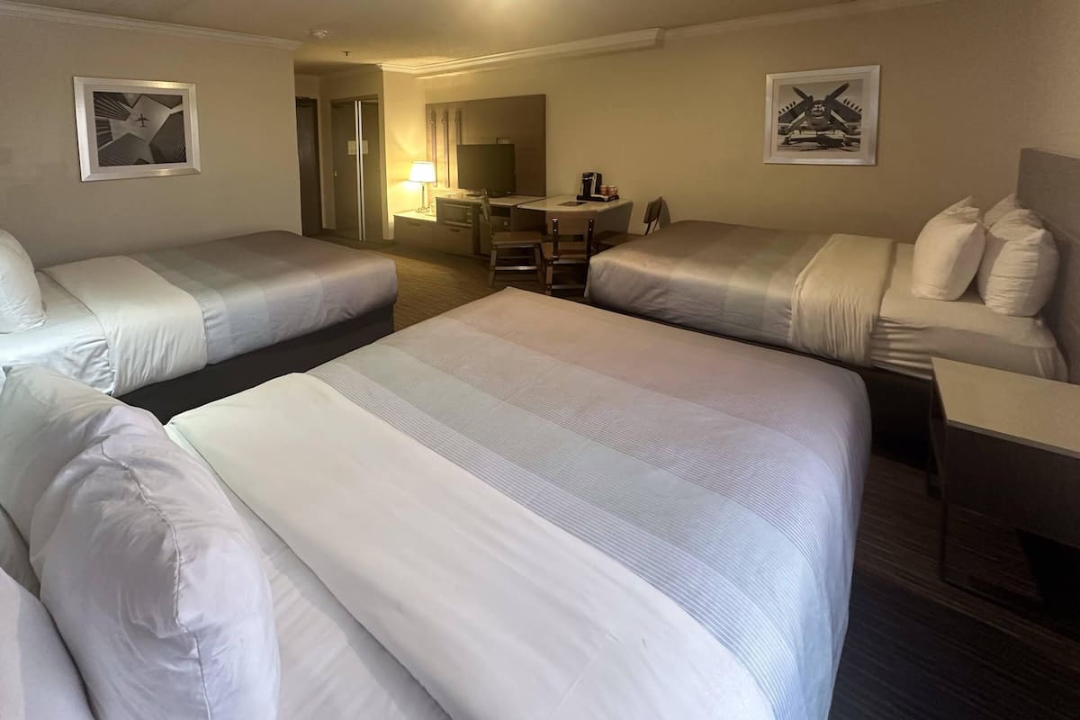 Ein Hotelzimmer mit zwei Betten, einem Schreibtisch, einem Stuhl und einem kleinen Tisch.