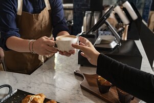 A person holding a cup of coffee at a counter.