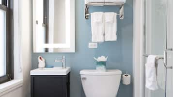 Un baño con inodoro blanco, lavabo con espejo y cabina de ducha de vidrio.