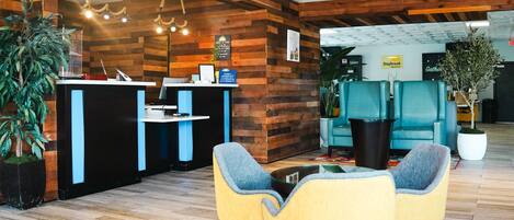 Un espace d’accueil moderne avec un lambris en bois, un comptoir d’accueil et un coin salon doté de chaises jaunes.