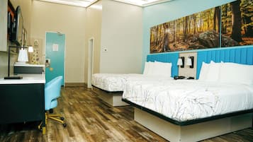 Una habitación de hotel con cama, escritorio, silla y un cuadro de un bosque.