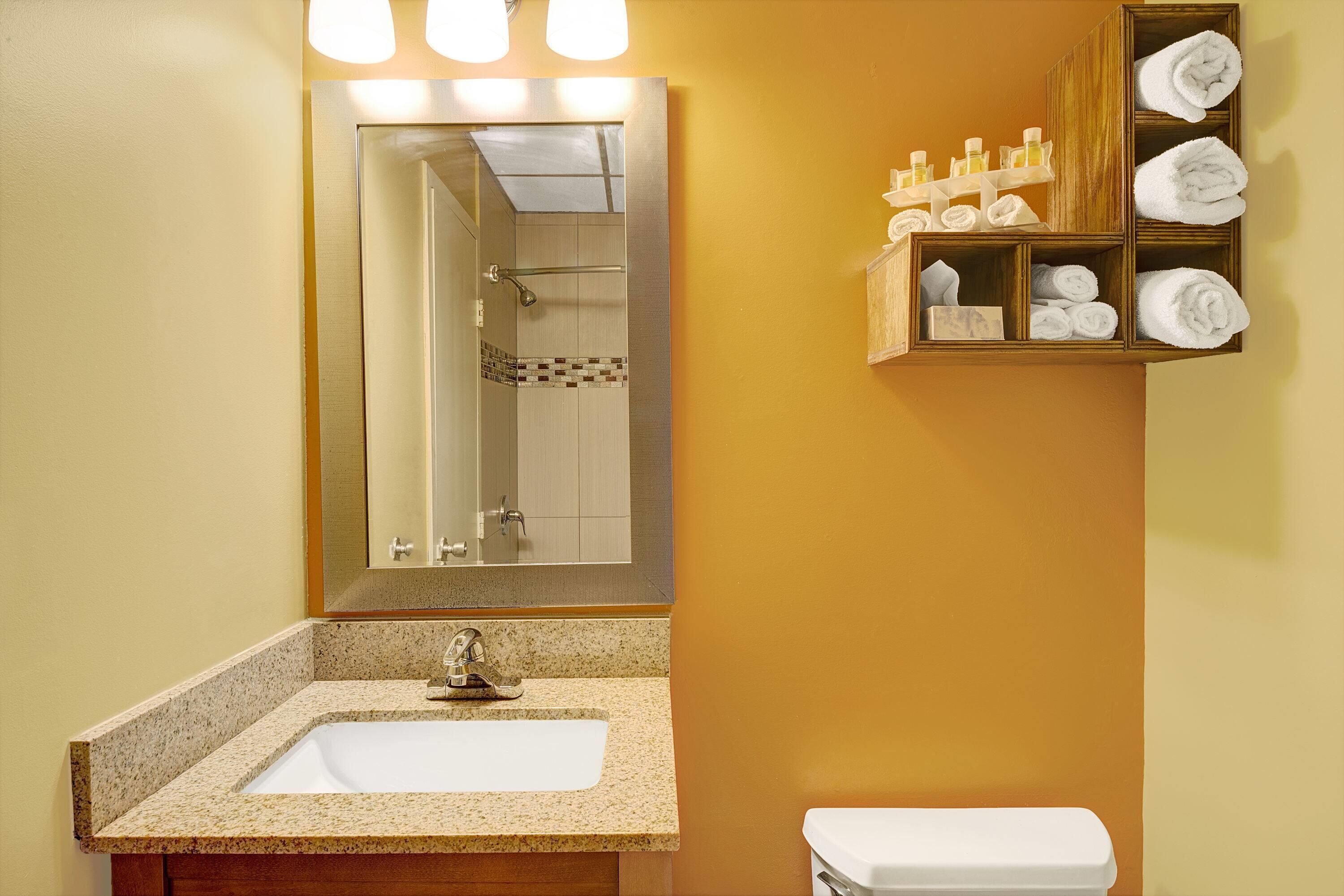 A bathroom with a sink, mirror, and towel storage.
