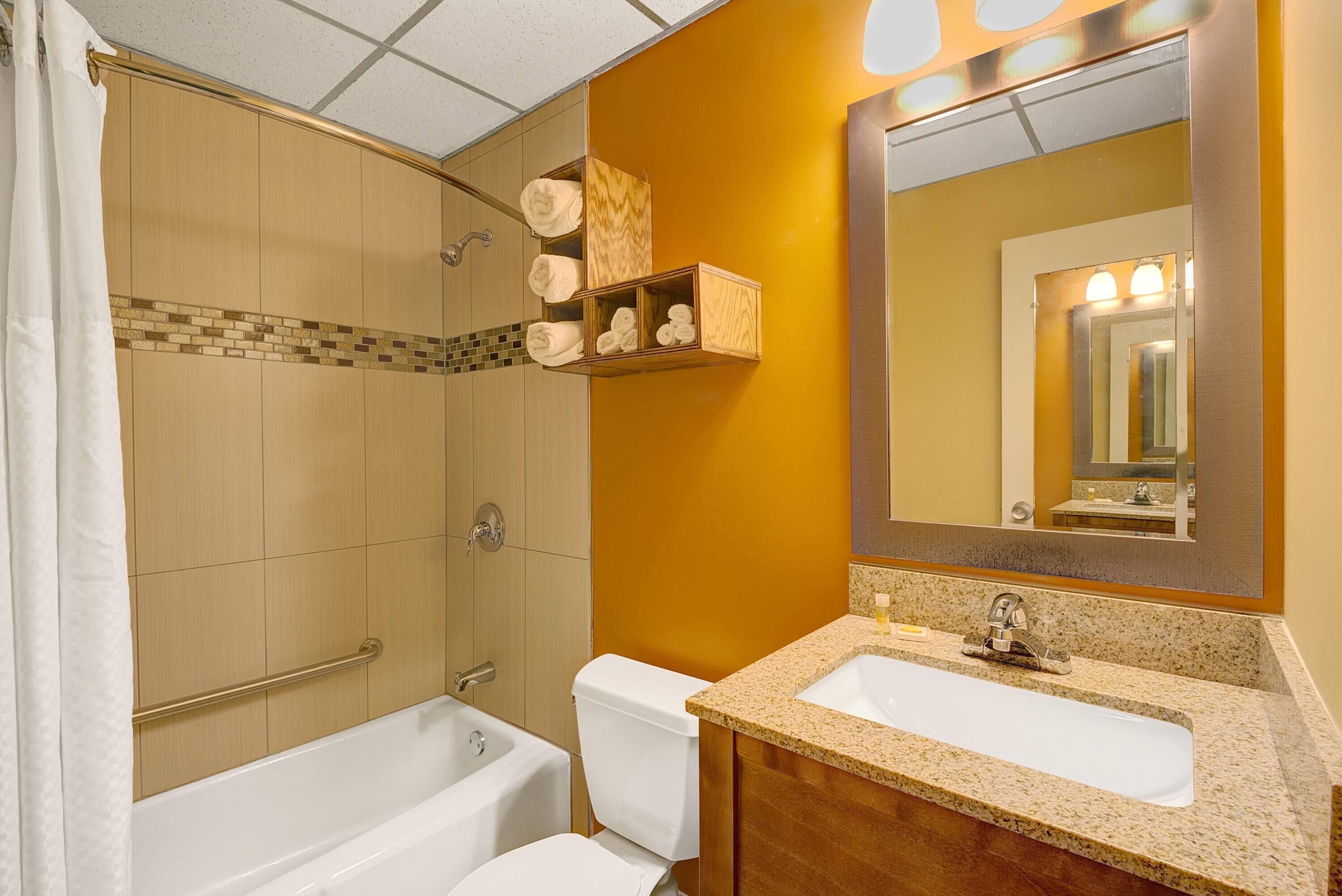 Ein Badezimmer mit Badewanne, Toilette und Waschtisch mit Waschbecken und Spiegel.
