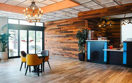 A modern interior with wooden panel walls, a reception desk, and a seating area with chairs.
