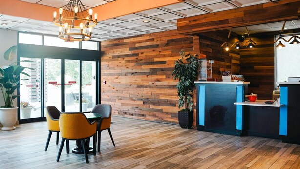 Un intérieur moderne avec des murs lambrés, un comptoir d’accueil et un espace détente avec des fauteuils.