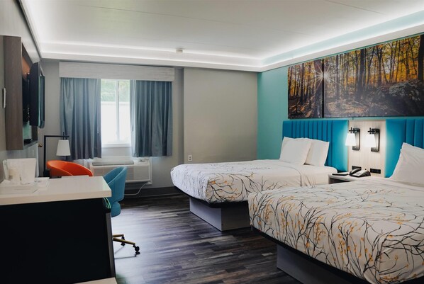A hotel room with two beds, a desk, a chair, a TV, and a large forest-themed painting on the wall. - Days Inn by Wyndham Southington (Southington)