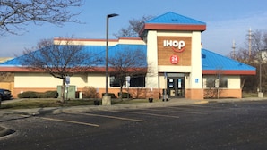 A IHOP restaurant with a blue roof, a parking lot, and a clear sky.