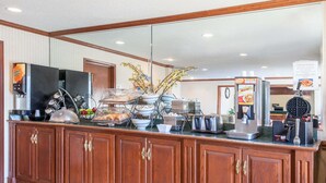 A buffet counter with various food items, a coffee machine, and a waffle maker.