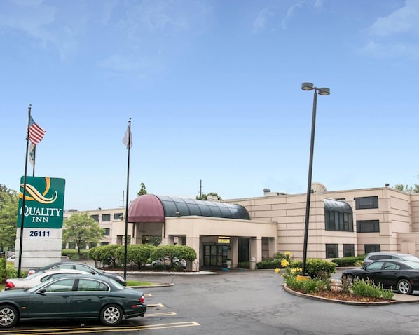 A Quality Inn hotel with a large parking lot, a dome-shaped building, and a flagpole with the American flag.