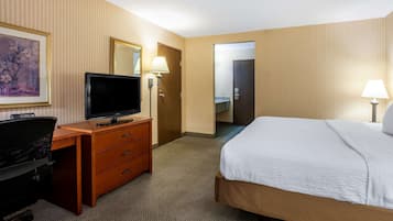 Una habitación de hotel con una cama, un escritorio con televisor, una cómoda y dos lámparas.