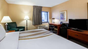 A hotel room with a bed, desk, television, and a window with curtains.
