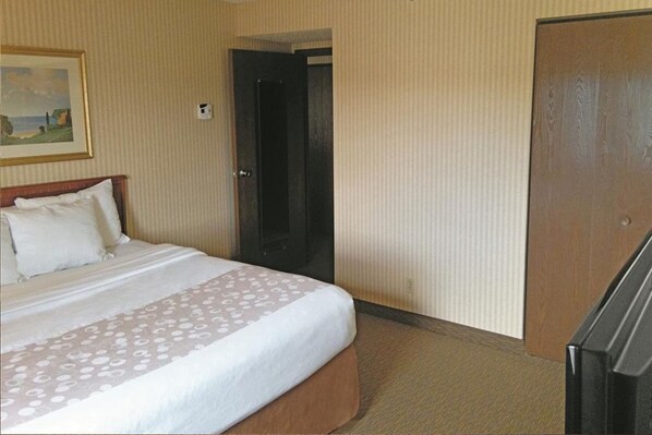 A hotel room with a bed, a door, and a television. - La Quinta Inn by Wyndham Detroit Southgate (Southgate)