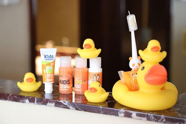A bathroom counter with children's toothpaste, shampoo, and a toy duck.