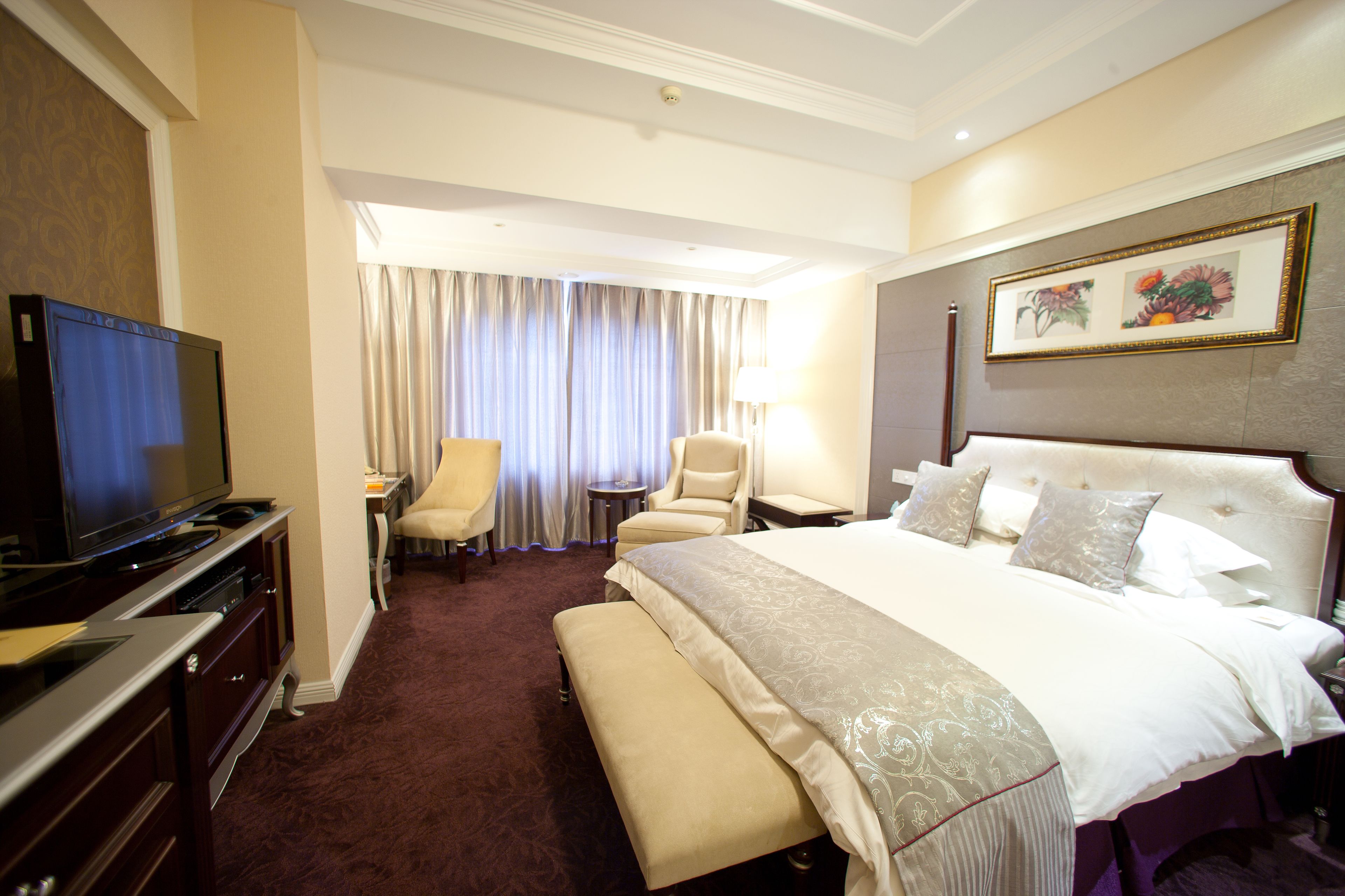 A hotel room with a large bed, a television, a desk, and a chair.