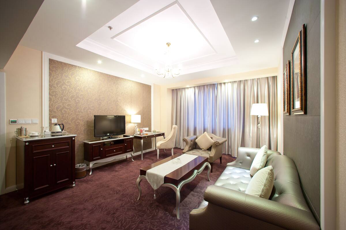Une chambre d’hôtel avec un grand lit, un canapé, une télévision, un bureau et une table à manger.
