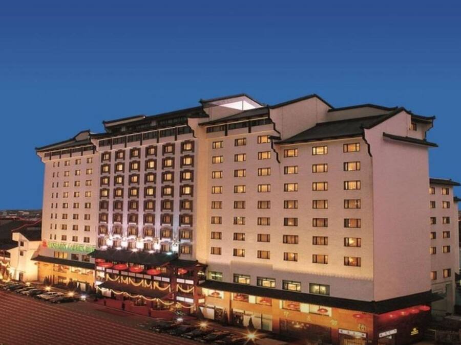 Un hotel de varios pisos con techo plano y un restaurante amplio en la planta baja.