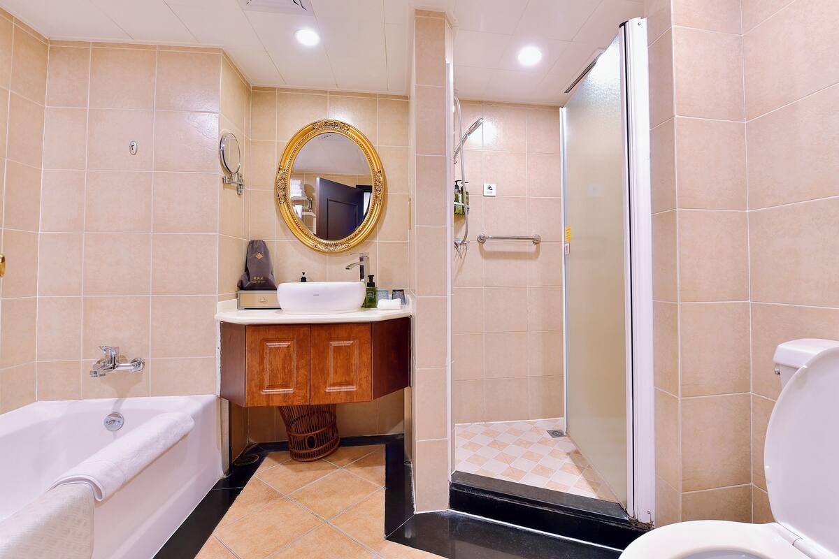 Une salle de bain moderne équipée d’une baignoire, d’un lavabo, d’un miroir et d’une douche.