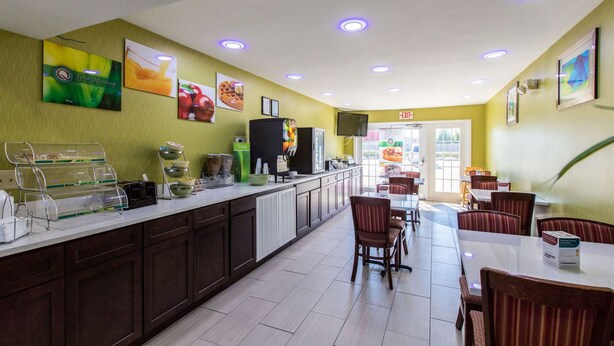 A breakfast area with a counter, seating, and a TV screen. - Quality Inn Albertville US 431 (Albertville)