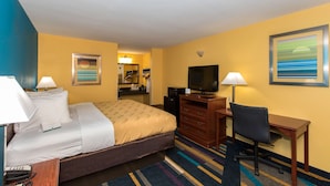 A hotel room with a bed, desk, chair, television, and a bathroom visible in the background. - Quality Inn Albertville US 431 (Albertville)