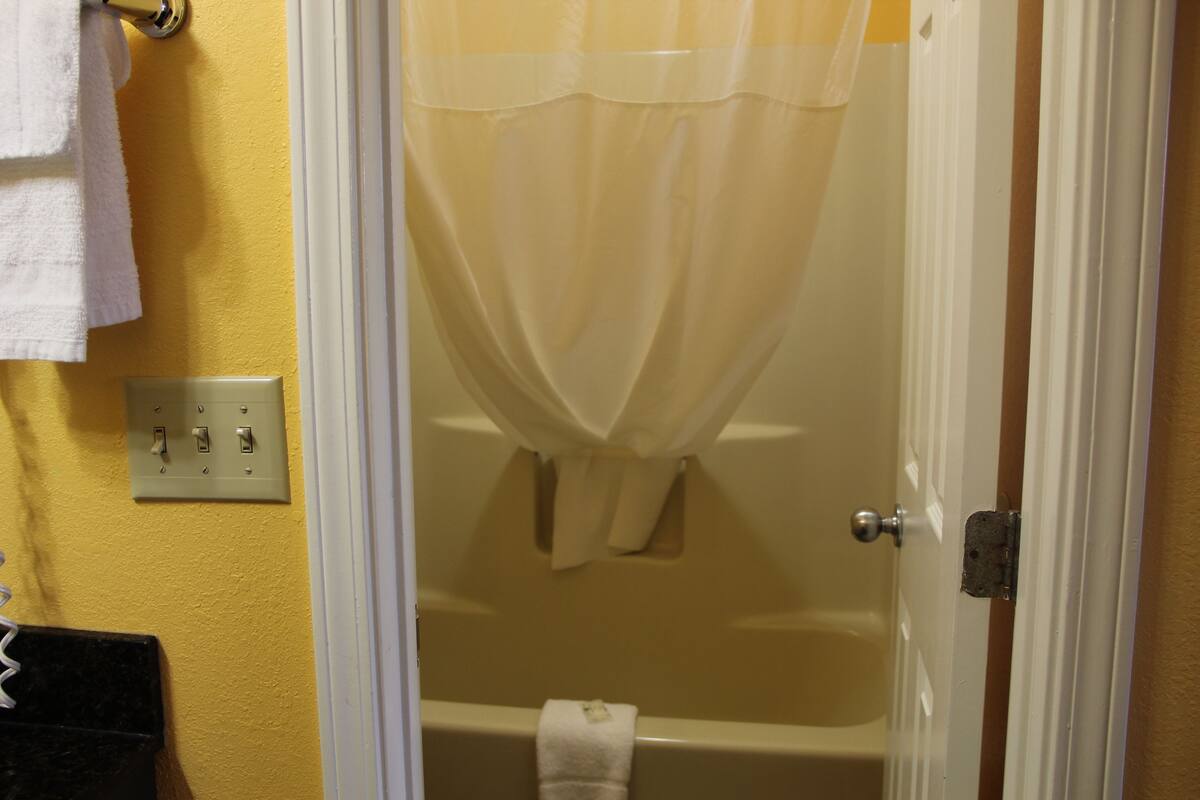 A bathroom with a bathtub, a shower curtain, and a towel hanging on the wall.