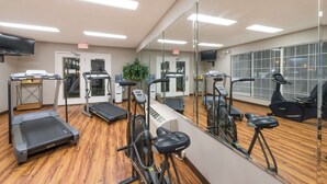 A gym with treadmills, stationary bikes, and a mirrored wall.