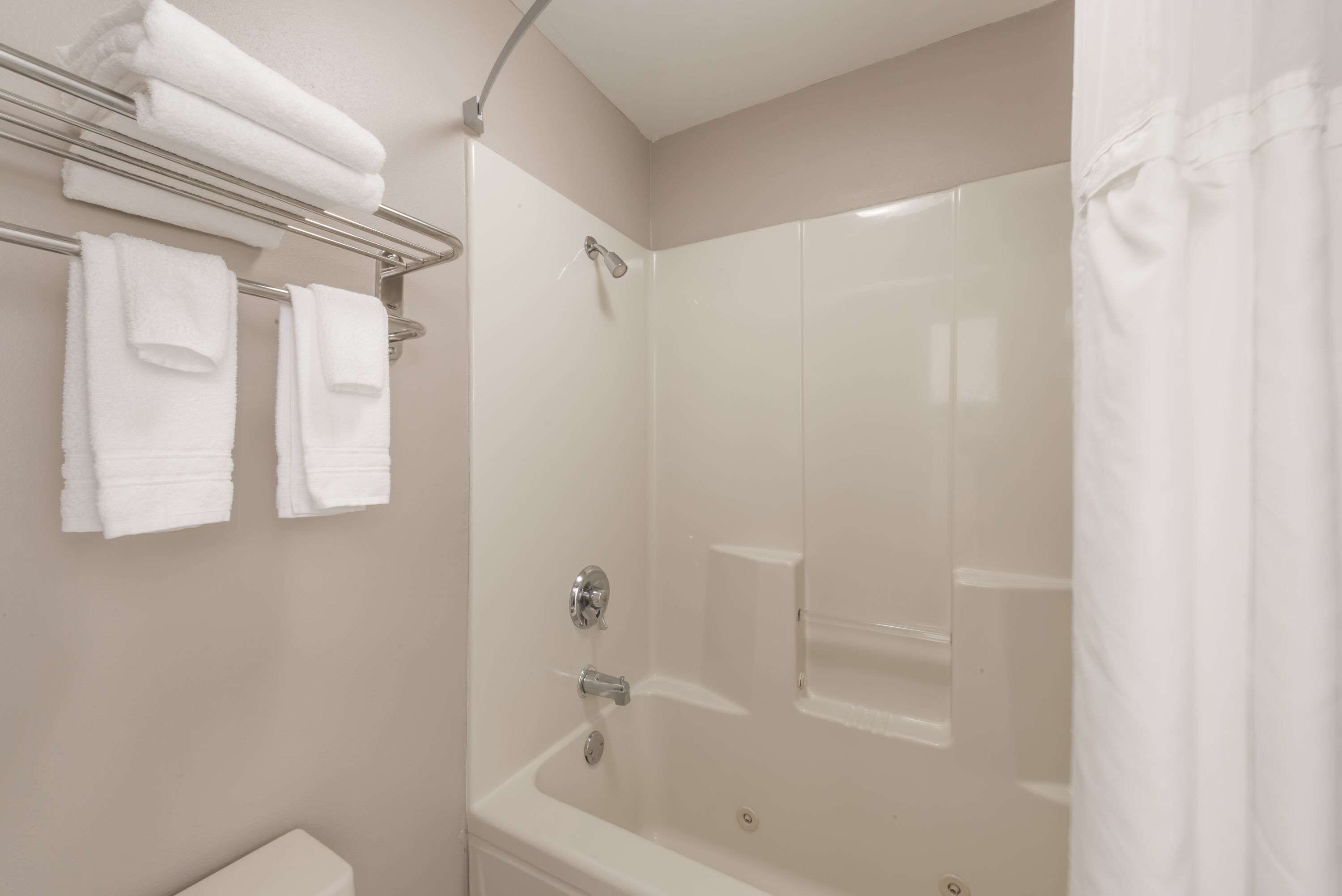 A bathroom with a bathtub, a shower, and a toilet. There are towels hanging on a rack.