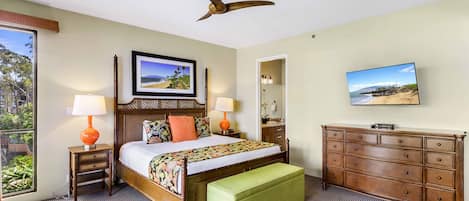 A hotel room with a bed, a green bench, a dresser, a ceiling fan, and two lamps.