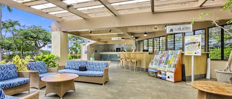 A covered outdoor seating area with wicker furniture and a bar.