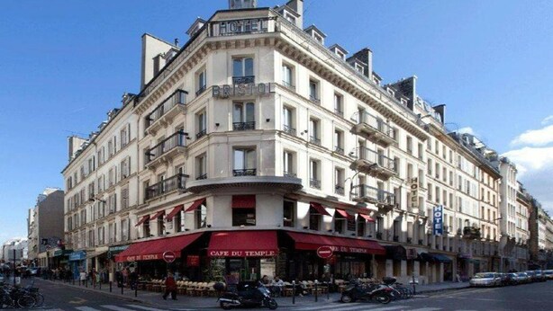 A corner building with a cafe on the ground floor, multiple floors, and a hotel sign on the top. - Bristol République (Paris)