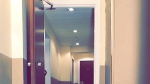 A hallway with a wooden floor, beige walls, and a door with the number 27. - Bristol République (Paris)