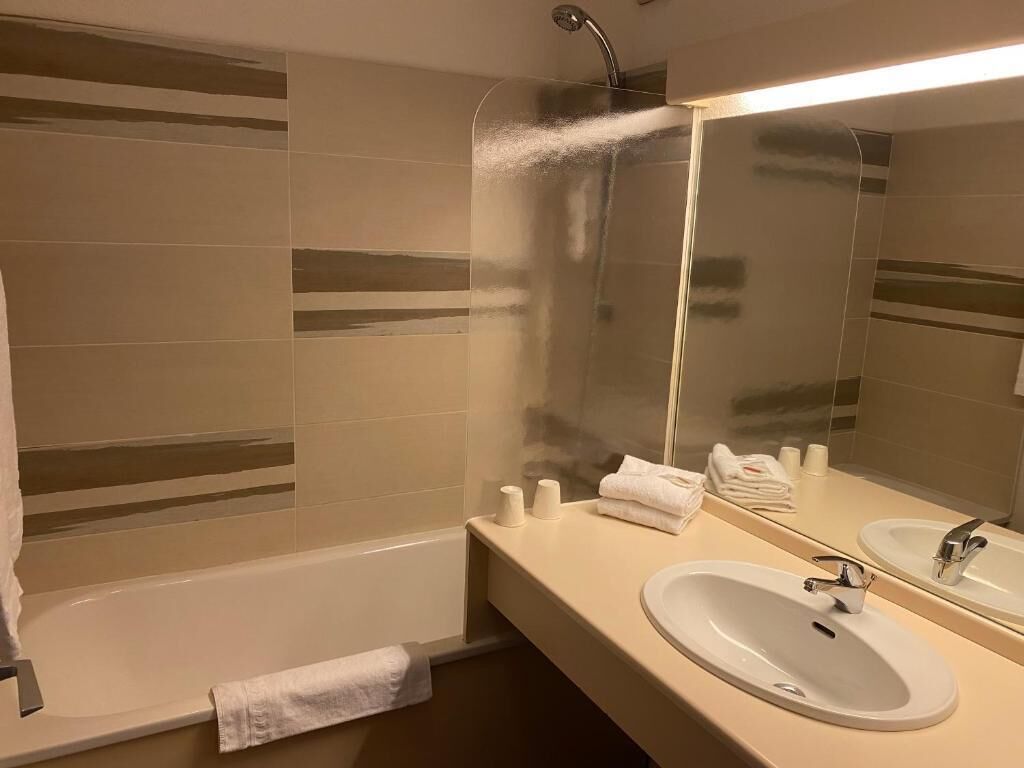 A bathroom with a bathtub, two sinks, a mirror, and a shower.