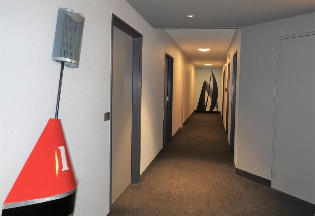 A hallway with carpeted floors, white walls, and doors.