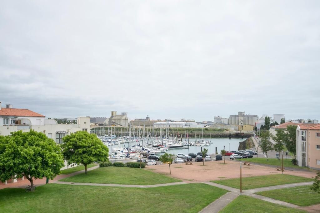 A marina with boats docked, surrounded by buildings and greenery.
