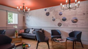 Een moderne woonkamer met een grote wereldkaart, een bank, twee fauteuils, een salontafel en een kroonluchter.