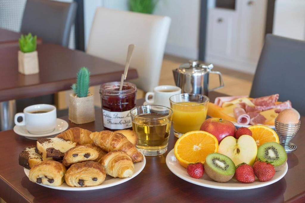 A breakfast table with croissants, fruit, eggs, and beverages.