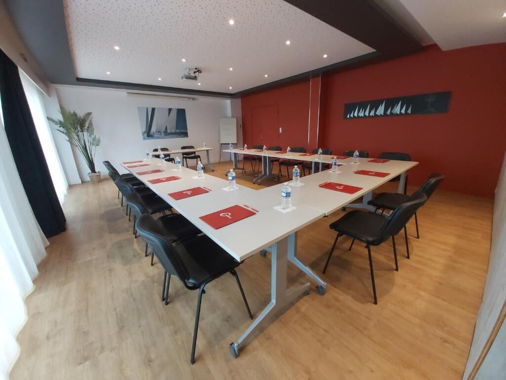 A conference room with a long table, black chairs, and a whiteboard.