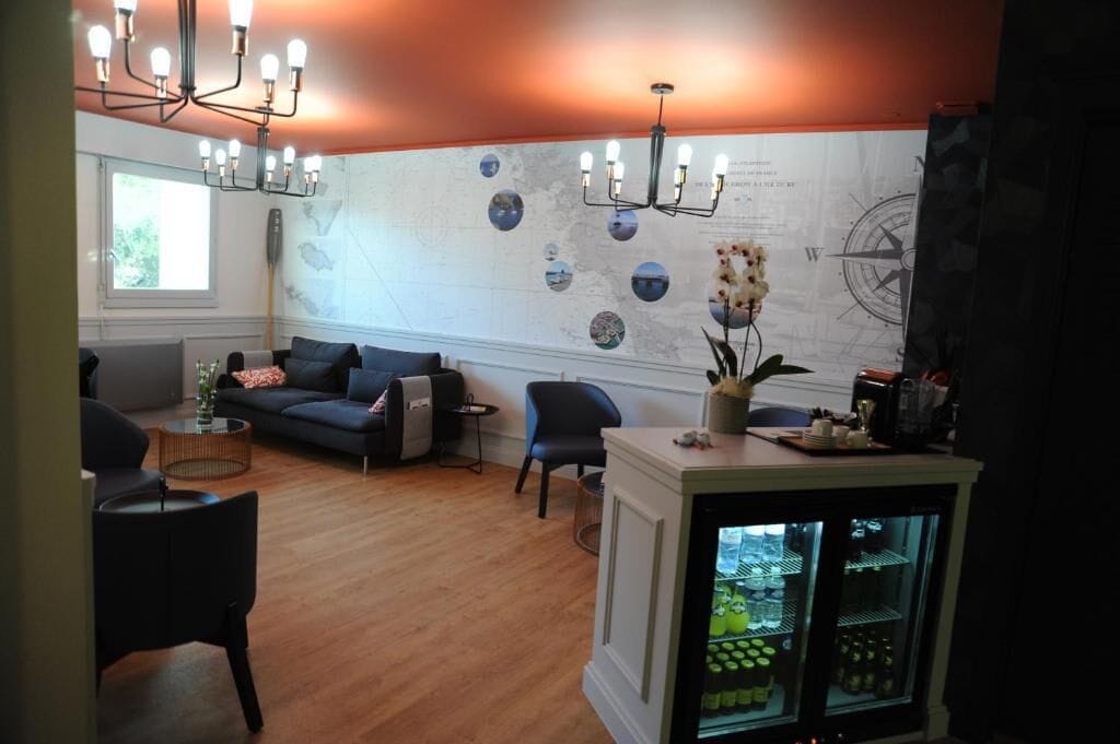 A modern living room with a sofa, chairs, a coffee table, a map on the wall, and a refrigerator.