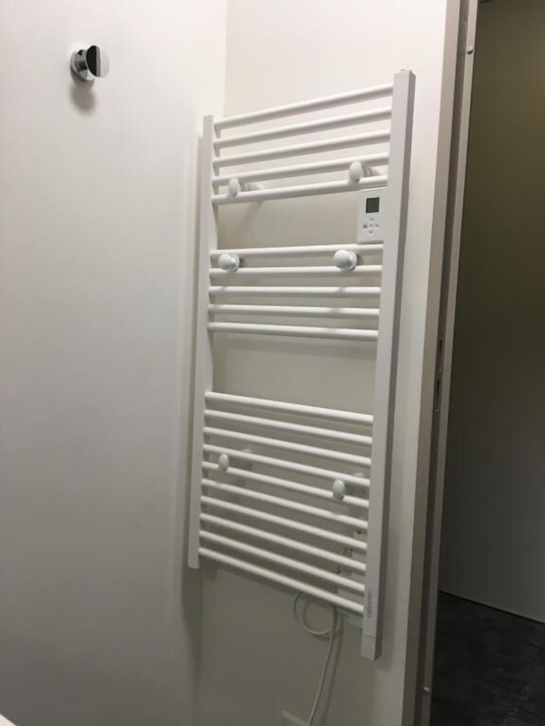 A white towel rack with multiple slots against a wall.