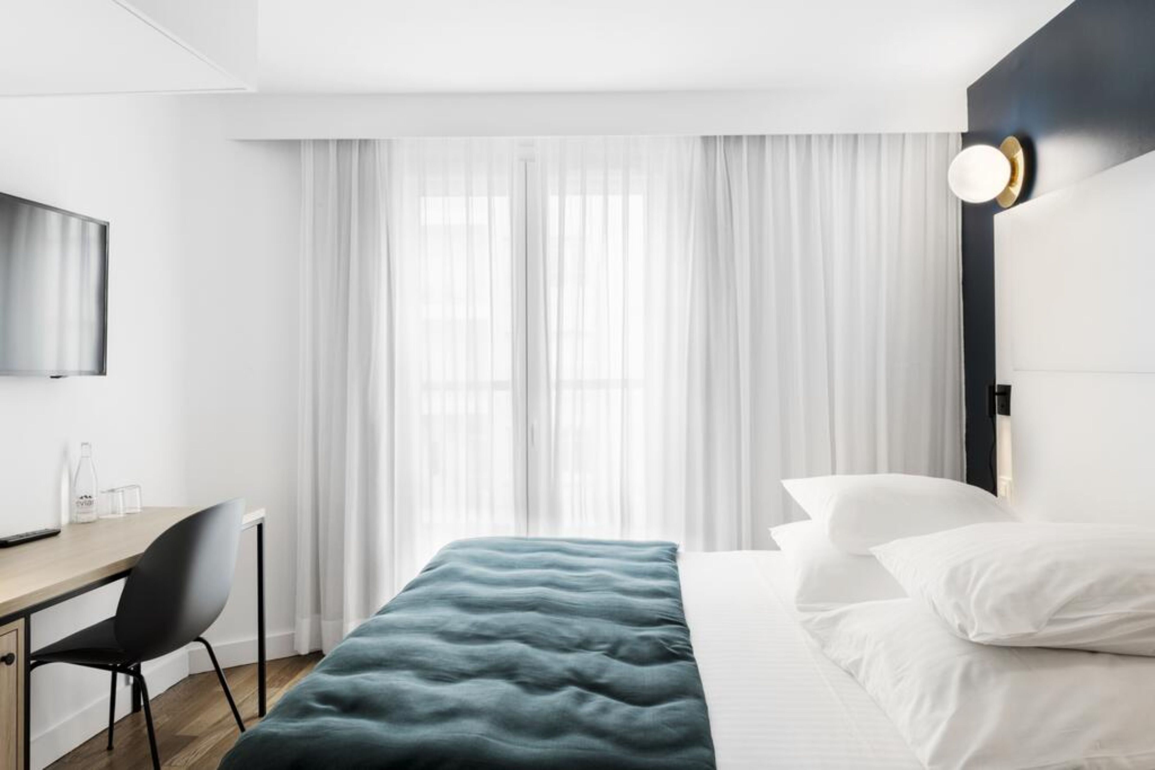 Una habitación de hotel moderna con una cama, un escritorio y un televisor.