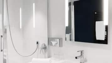 Une salle de bain moderne avec une douche à parois de verre, un lavabo blanc et un grand miroir.