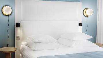 Un dormitorio moderno con una cama grande, dos mesitas de noche y luces fijadas a la pared.