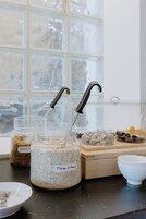 A kitchen counter with jars of grains, a wooden box, and a white bowl.