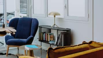 A modern living room with a blue armchair, a yellow sofa, a small round table, and a floor lamp.